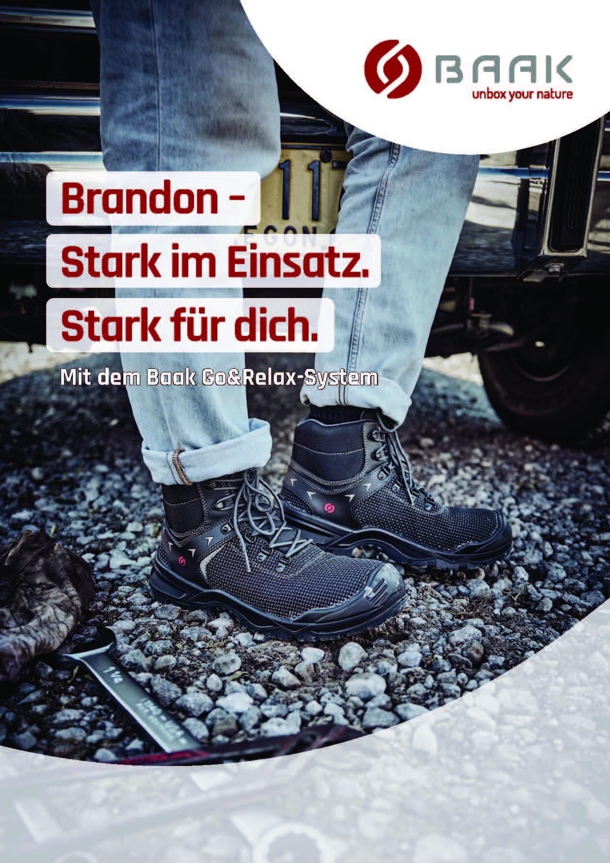 A man wearing safety boots is standing on a rocky surface with tools lying on it