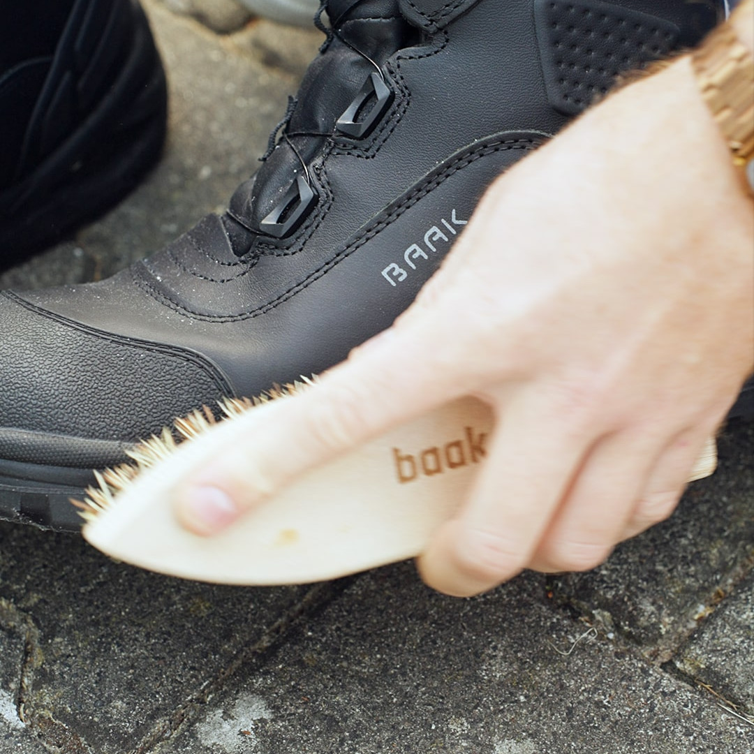 Eine Hand, die mit einer Schuhb&uuml;rste den Schuh putzt