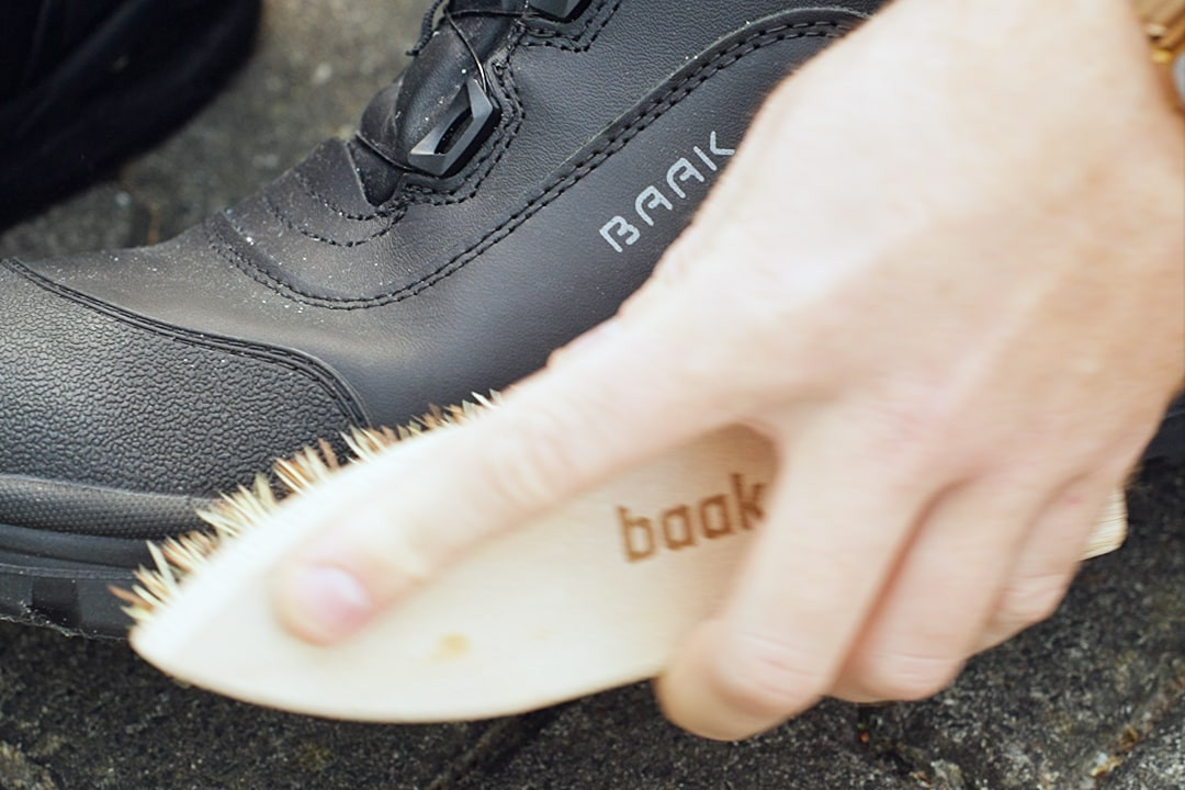 Eine Hand, die mit einer Schuhb&uuml;rste den Schuh putzt