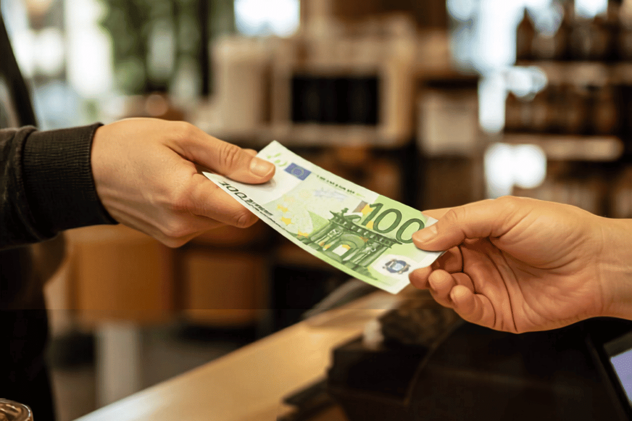 Close-up of two hands as a 100-euro bill is handed over
