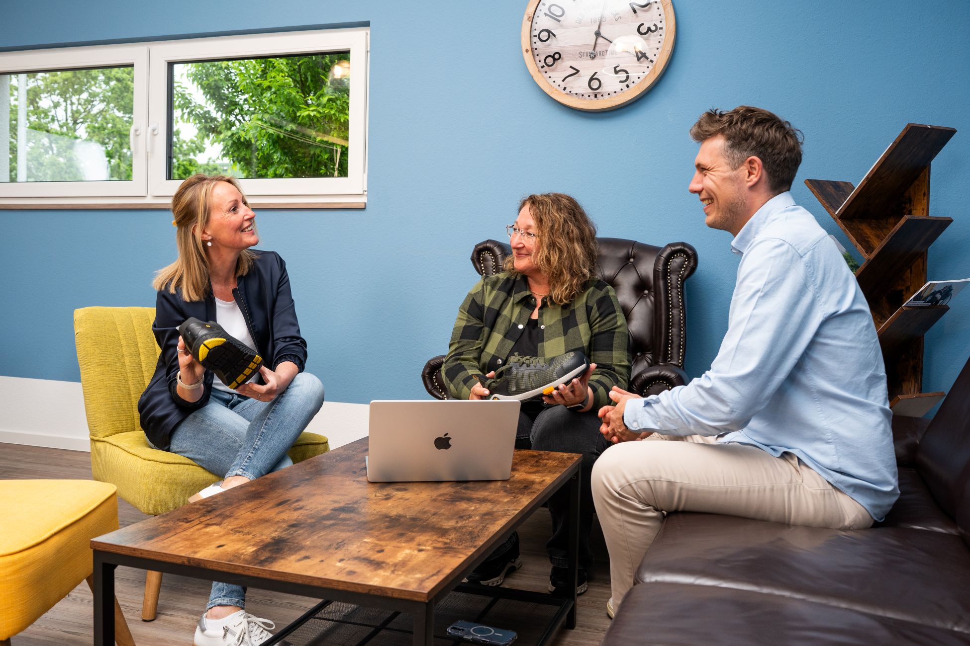 Zwei Frauen und ein Mann sitzen auf Loungem&ouml;beln und unterhalten sich angeregt
